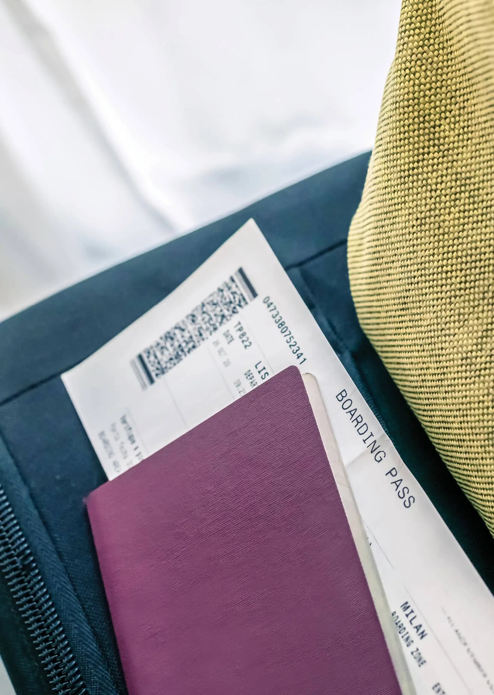 A boarding pass and passport resting on a travel bag