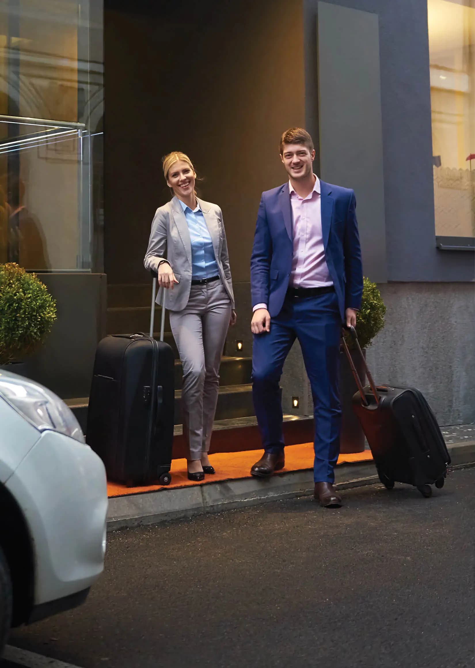 Two business travelers arriving at a hotel with luggage
