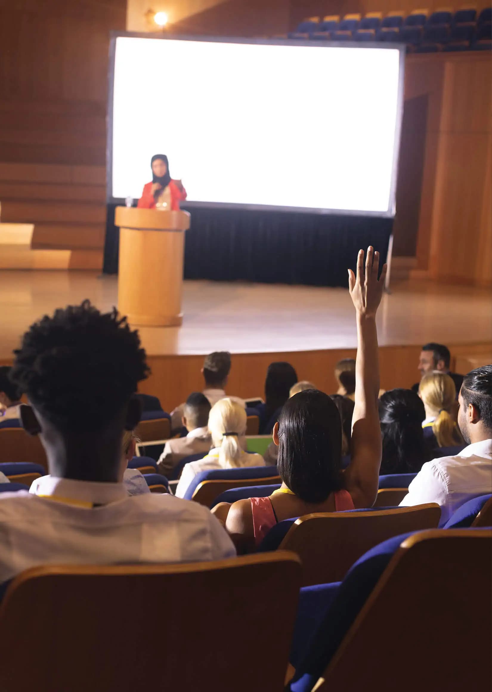 An audience member raising a hand at a conference presentation