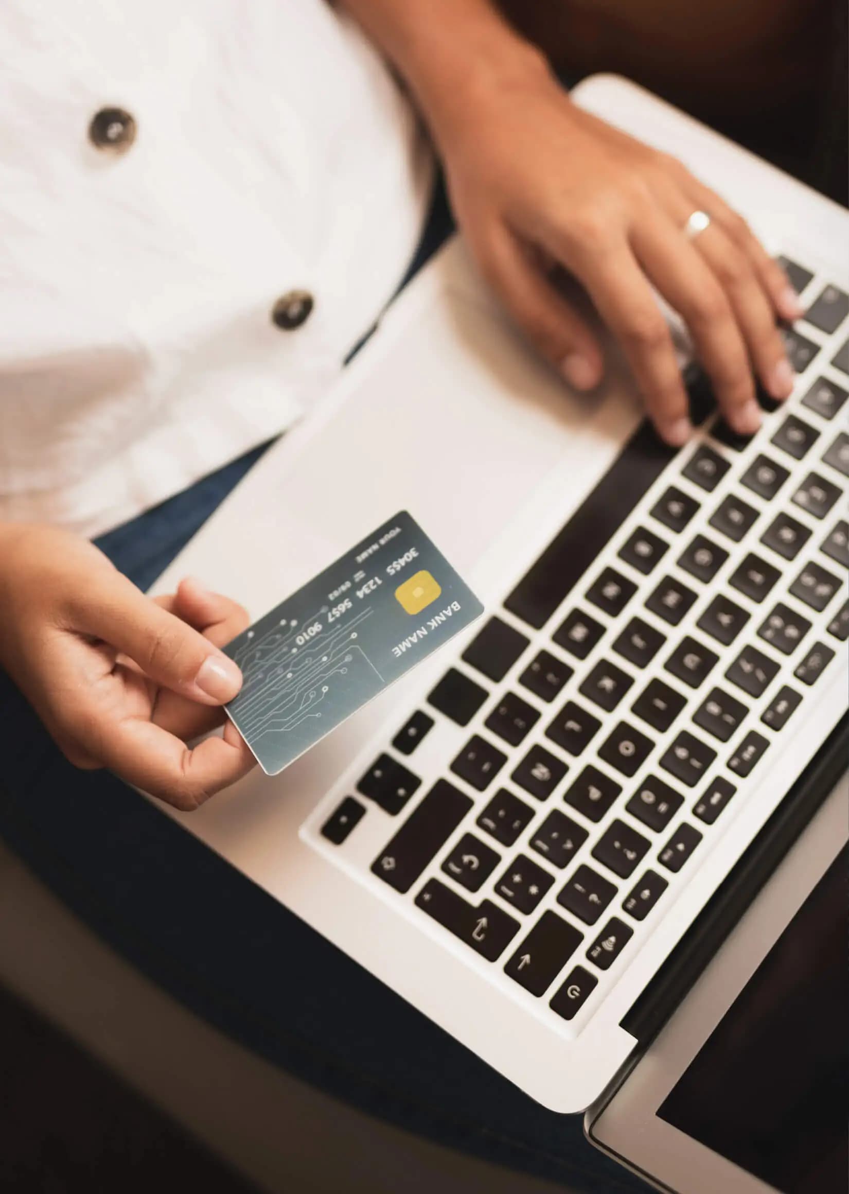 A person holding a corporate card while working on a laptop