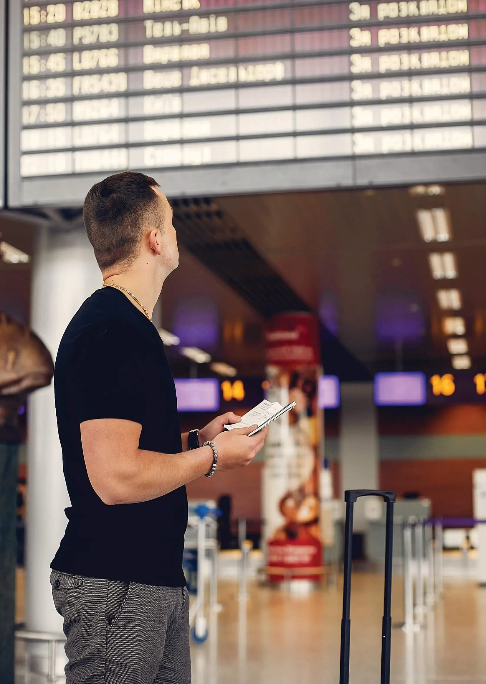 A traveler checking a departures board at an airport